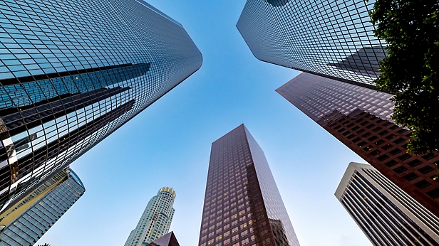 Upward view of skyscrapers against a clear blue sky.