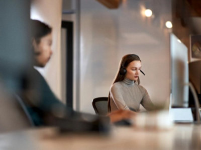 A person wearing a headset and sitting at a desk