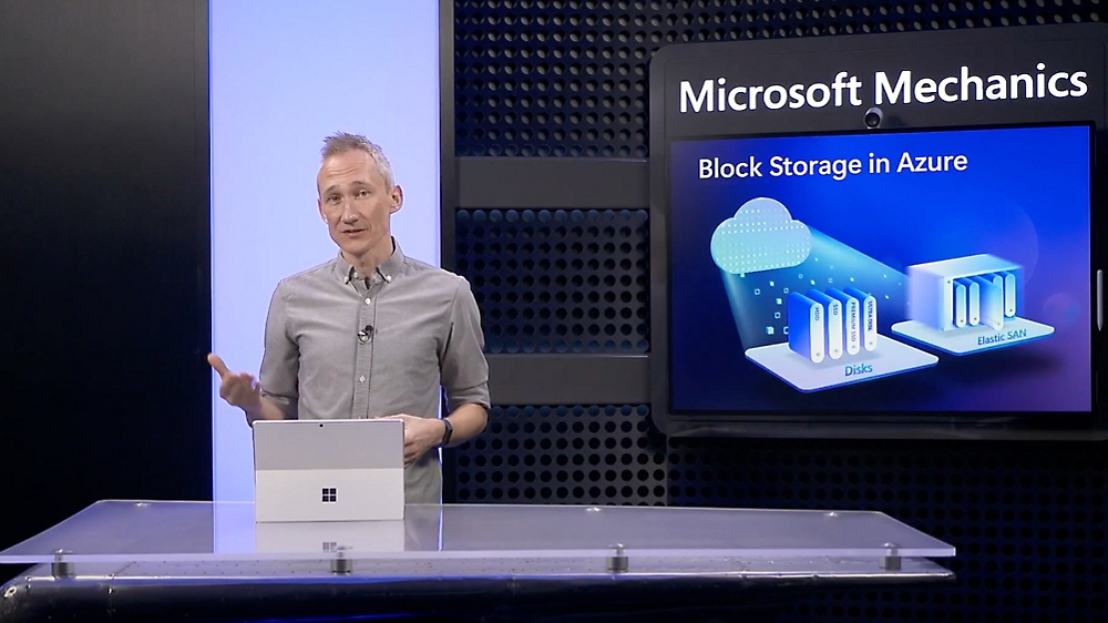 A presenter stands next to a screen displaying "Microsoft mechanics" and a graphic on block storage in azure
