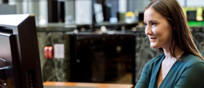 A woman in a green top smile while using a computer.