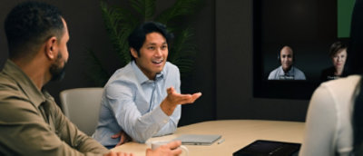 A diverse group of professionals engaged in a hybrid meeting, with three people in a conference room.