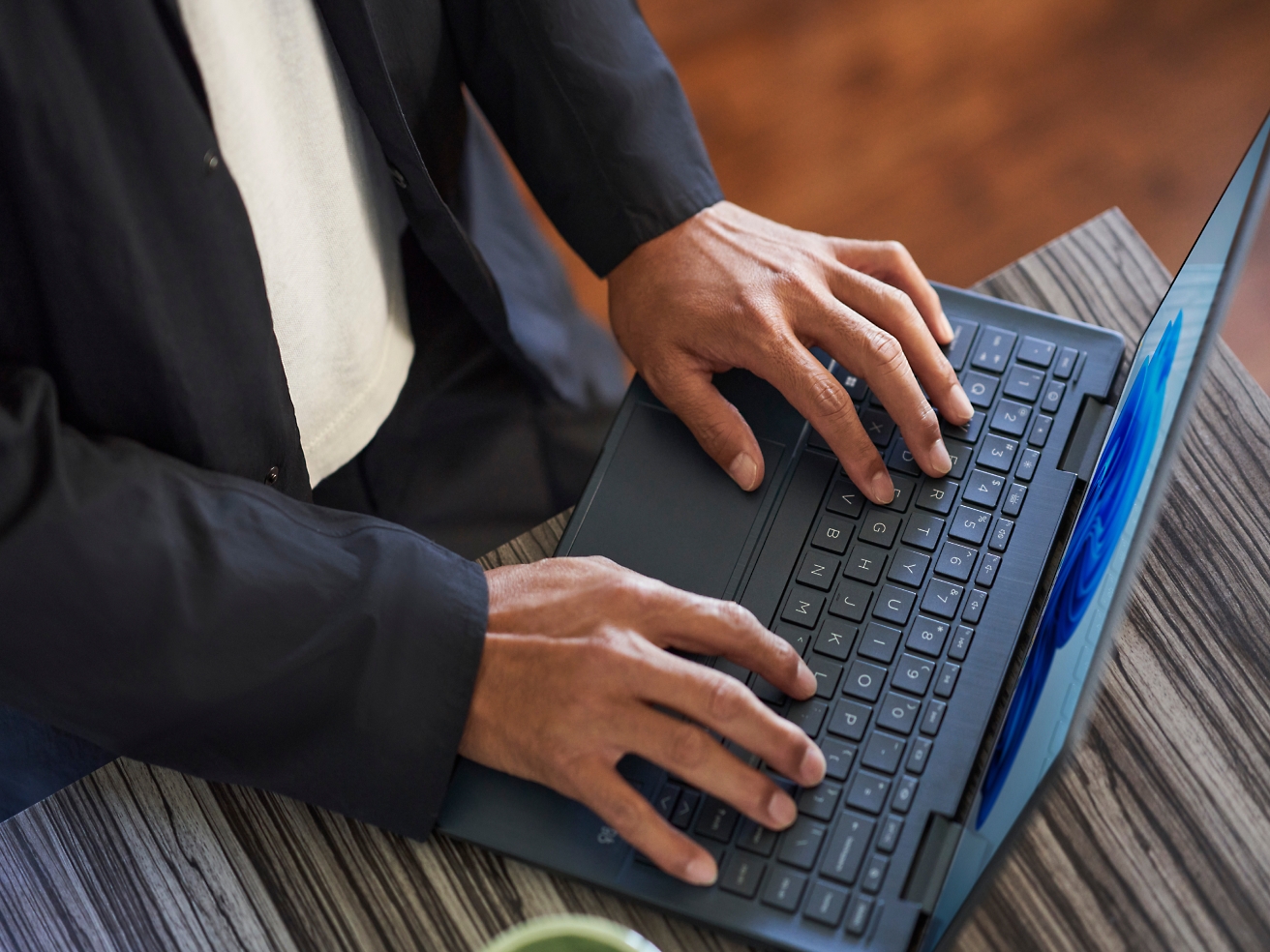 A person in a business suit typing on a laptop keyboard