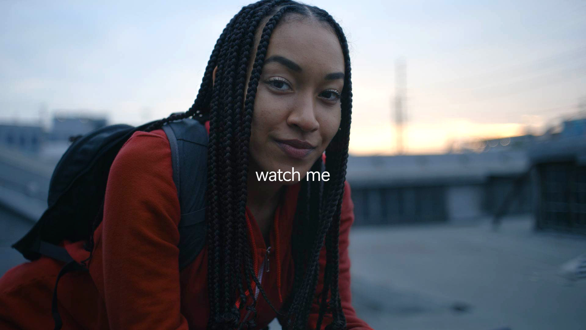 Confident woman sitting outside wearing a red shirt and a backpack