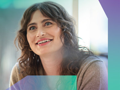 A woman with curly hair is smiling at the camera.