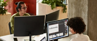 A man wearing glasses works on a computer near a screen displaying the text Craftsaunship.
