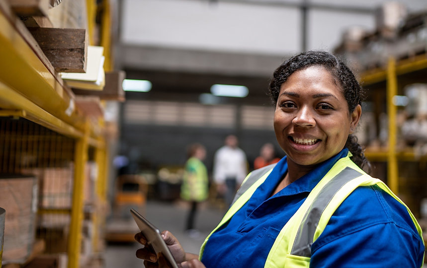 A woman in a warehouse setting holding a tablet