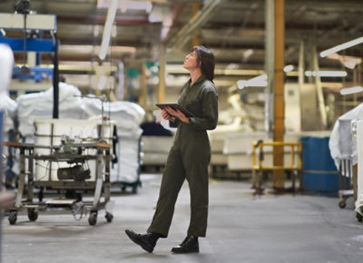 Travailleur dans une usine portant un bleu de travail et tenant une tablette
