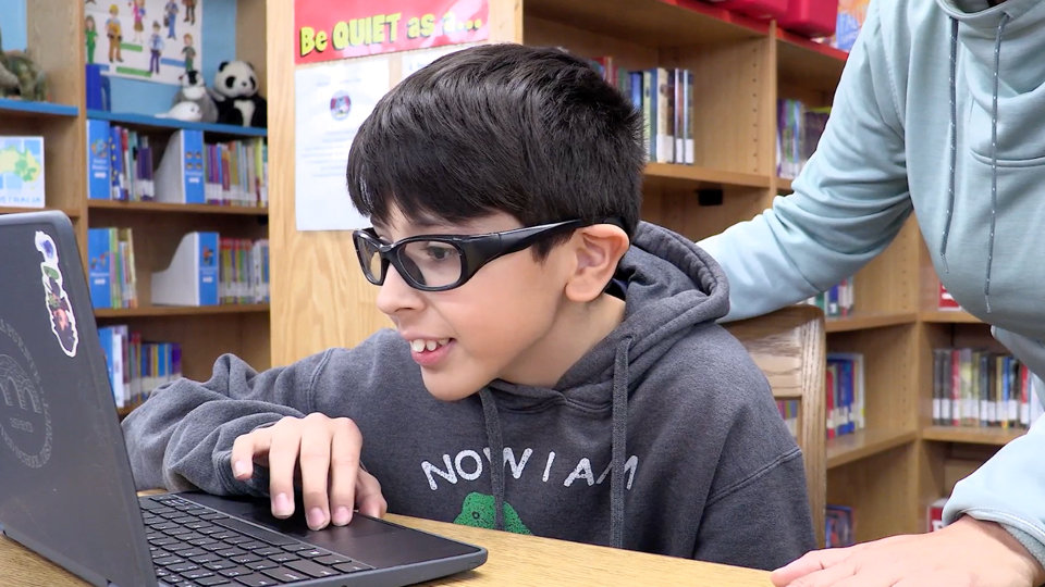 A child using a laptop in a library.