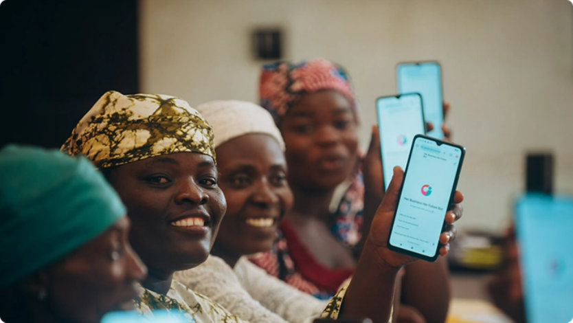A group of smiling women hold up smartphones displaying an app.