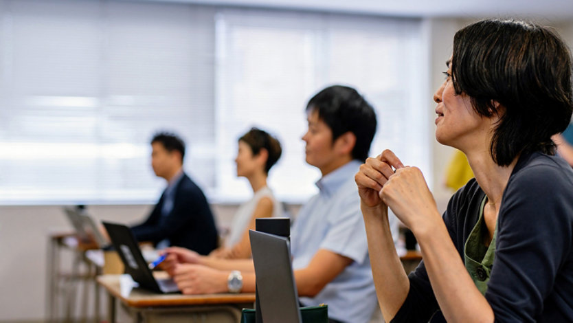A student focused on a laptop in a classroom.