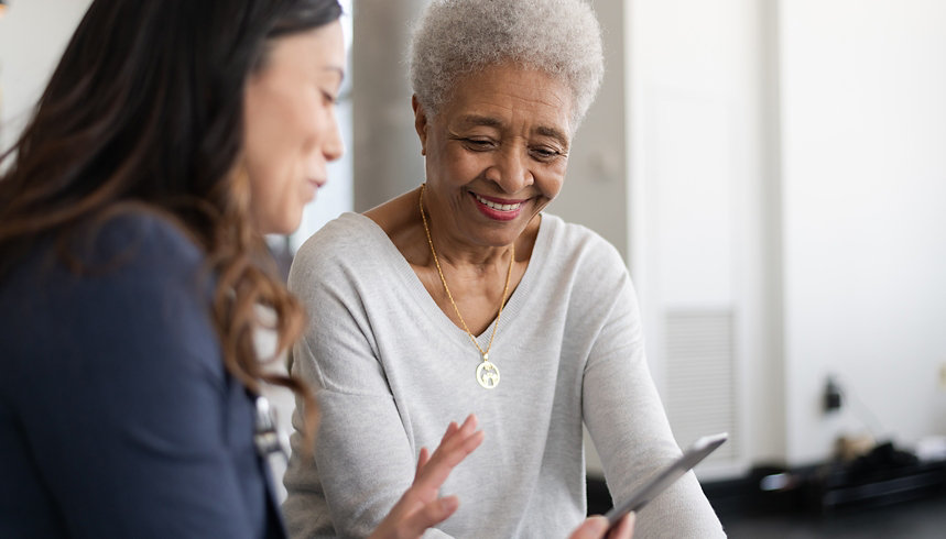A senior patient and caretaker looking at a mobile phone.