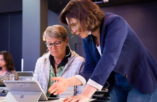 A woman assisting another person with a tablet.