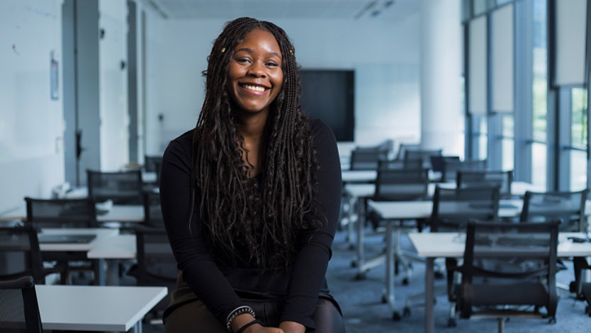 A woman smiling in an empty classroom.