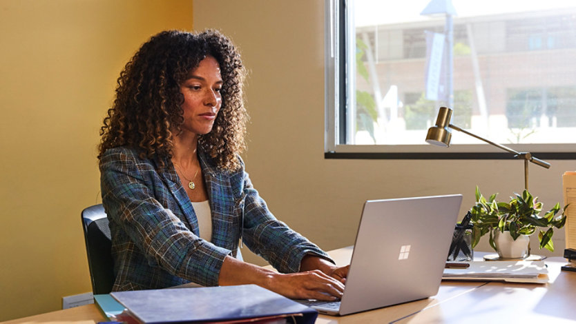 A woman working on a laptop at her desk.