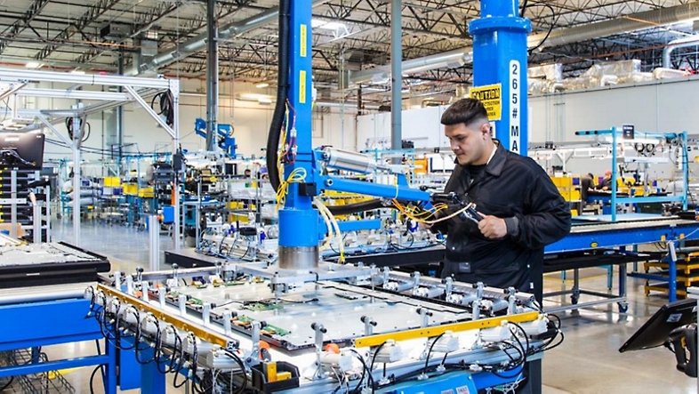 En fabriksmiljö där en anställd arbetar med en maskin.