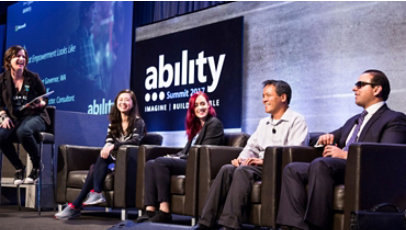 A panel of five people sit on a stage at an event.