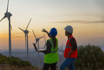 Two energy workers out in the field looking at wind turbines.