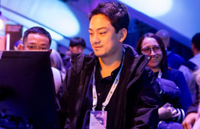 Person using a computer at a crowded tech event booth