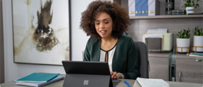 A person sitting at a desk looking at a laptop.