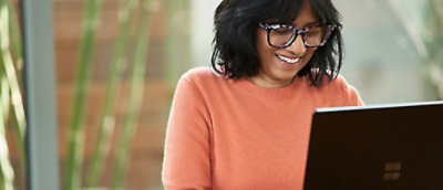 A woman wearing glasses looking at a laptop.