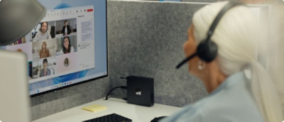 A person wearing a headset and looking at a computer screen.