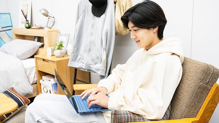 男性が膝の上で Surface Laptop をのせて勉強している