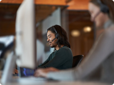 A person in black shirt wearing headphone working on laptop 