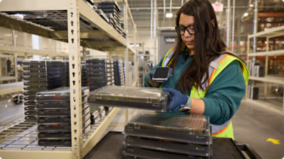 Worker scanning electronic devices in a warehouse.