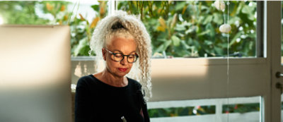 A woman sitting at a computer looking out a window.