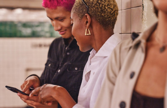 A group of young people looking at a Smart Phone.