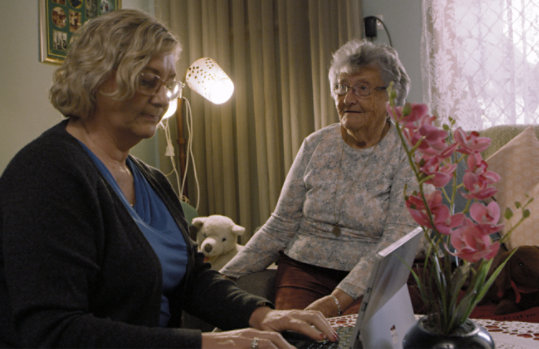 A nurse using a Surface, assisting an elderly patient.