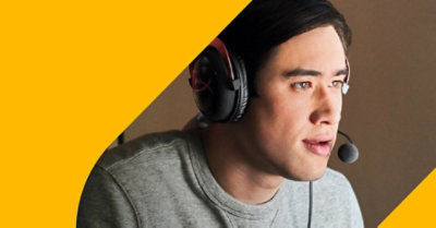 A person standing in their home office looking at a desktop monitor.