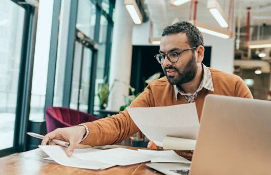 Employee shuffling paperwork at a desk.