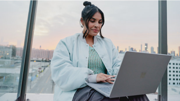Female adult sitting outside typing on a Surface Laptop 5.