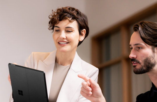 A man and woman looking at a Platinum Surface Pro in tablet mode. 