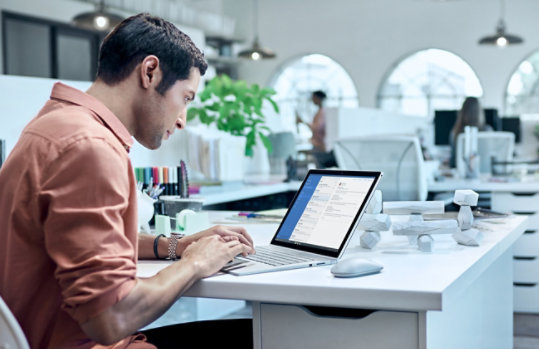 une personne utilise un Surface Book sur son bureau au travail