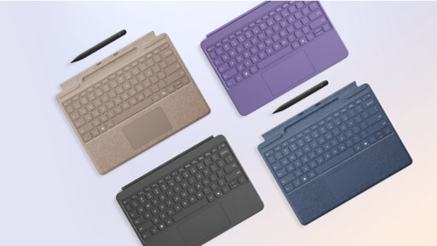 A family of Surface Pro keyboards in various colors and sizes, shown with accompanying slim pens. One each of Dune and Sapphire 13-inch keyboards, and one each of Slate and Violet 12-inch keyboards.