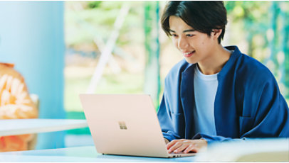 学生が教室の机でサンドストーンのSurfaceLaptop5を眺めている画像