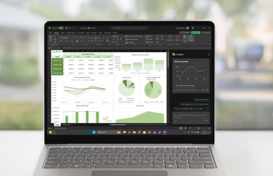 A Surface Laptop for Business sits open on a table displaying the Excel app with Copilot assisting inside a spreadsheet.