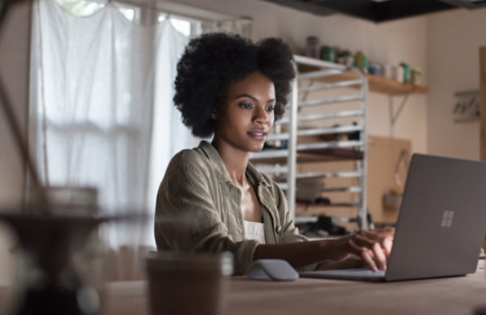 Une femme utilise son Surface Laptop à son bureau.