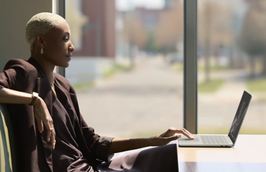 Uma pessoa sentada a uma mesa a trabalhar num Surface Laptop para Empresas, num ambiente bem iluminado
