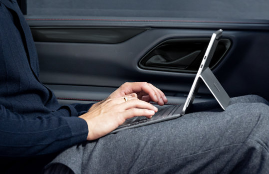 En person som sitter i en bil mens han taster på 12-tommers Surface Pro Keyboard, koblet til en Surface Pro.