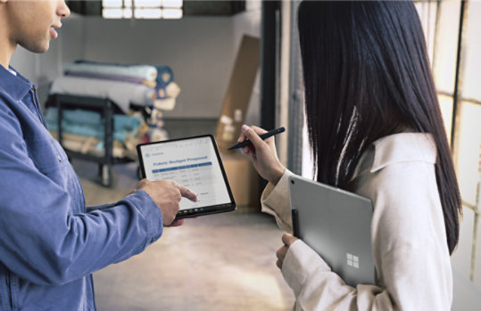 Duas pessoas seguram dispositivos Surface Pro para Empresas enquanto utilizam a Slim Pen.
