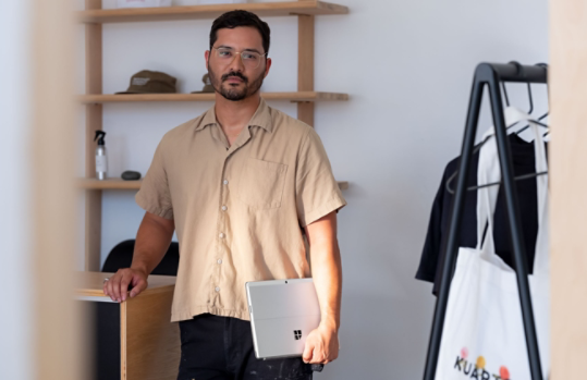 A person holding Surface Pro X in their business.