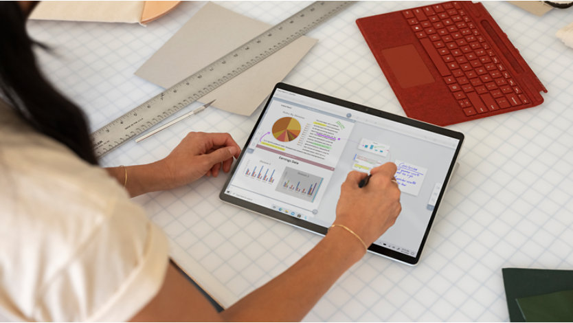 An individual using a Surface Pro X on a work surface. 