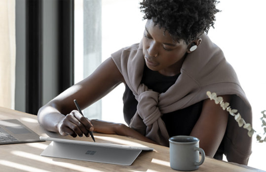 A person writing on Surface Pro 8 at their desk.