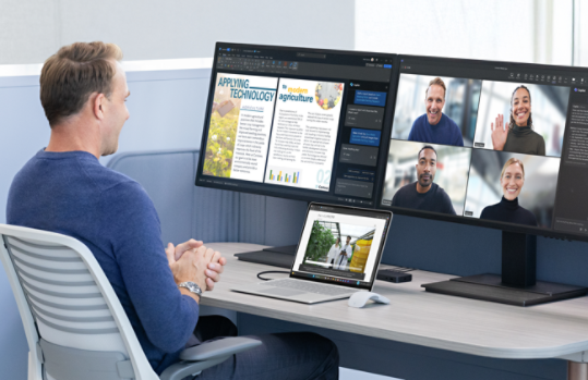 A person seated at a desk on a video call, using Surface Laptop for Business’s camera while working across multiple monitors.