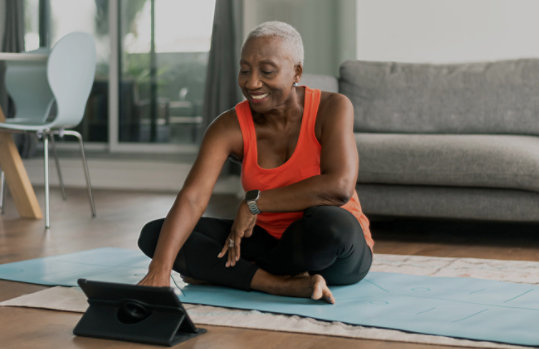 A person on a yoga mat working using a laptop.
