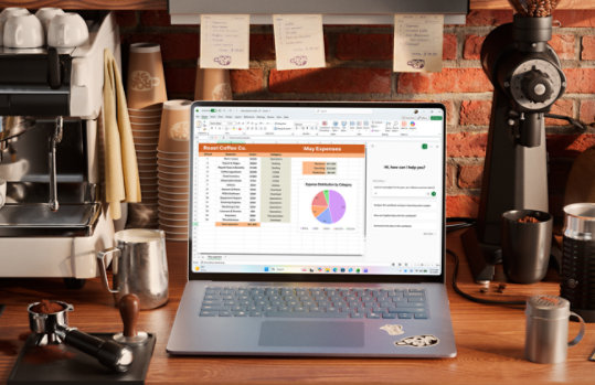 A blue laptop on a café counter displays a spreadsheet dashboard with charts.