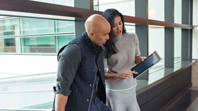 שני אנשים משוחחים בחדר פגישות, אחד מהם מצביע על מסך של מחשב נישא